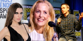Panel at Comic-Con featuring three speakers: a woman in a black dress on the left, a smiling blonde woman center, and a man in a plaid shirt speaking into a microphone on the right, with Comic-Con banners in the background.