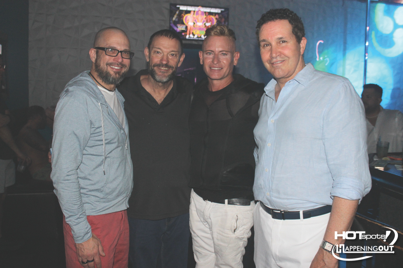 Four men posing together in a nightclub, smiling at the camera during a night out.