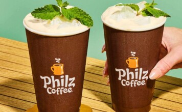 Two iced coffee drinks in brown Philz Coffee cups with mint garnish on a wooden table.