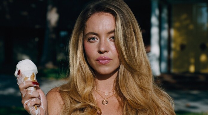 Sydney Sweeney Defends Euphoria Nudity, Talks About Double Standard for Women On Screen Young woman with long blonde hair holding a vanilla ice cream cone outdoors, looking at the camera.