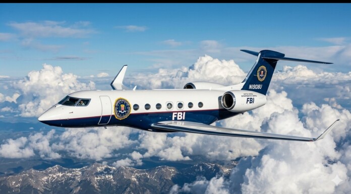 FBI business jet in flight above white clouds and a mountain range.