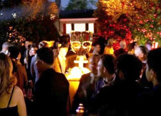 Grindr White House Correspondents Dinner Party Felt More Straight Than Queer Crowd of people at a nighttime outdoor party around a glowing champagne tower centerpiece on a pedestal outside.