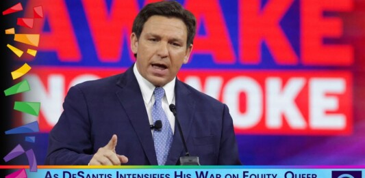 Male speaker in a navy suit delivers a televised speech, with a bold red backdrop and a blue caption bar reading: 'As DeSantis Intensifies His War on Equity, Queer God Squad Says God’s Realm is Based on DEI'