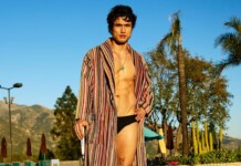 Charles Melton Heats Up Men’s Health Ahead Of Beef Season 2 Premiere Man in a striped robe over black swim briefs posing poolside at a sunny resort with palm trees in the background