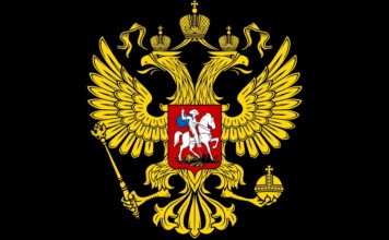 Gold double-headed eagle with crowns, scepter, and orb on a black field, bearing a red shield with a mounted knight (Russian coat of arms).