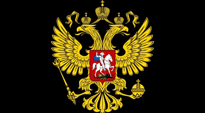 Russian Outlet Fined $6.6K Over Review of Gay Hockey Drama Under ‘LGBT Propaganda’ Law. Gold double-headed eagle with crowns, scepter, and orb on a black field, bearing a red shield with a mounted knight (Russian coat of arms).