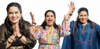 Three smiling women of Indian descent raise their hands in celebration against a white background, wearing colorful outfits and jewelry.