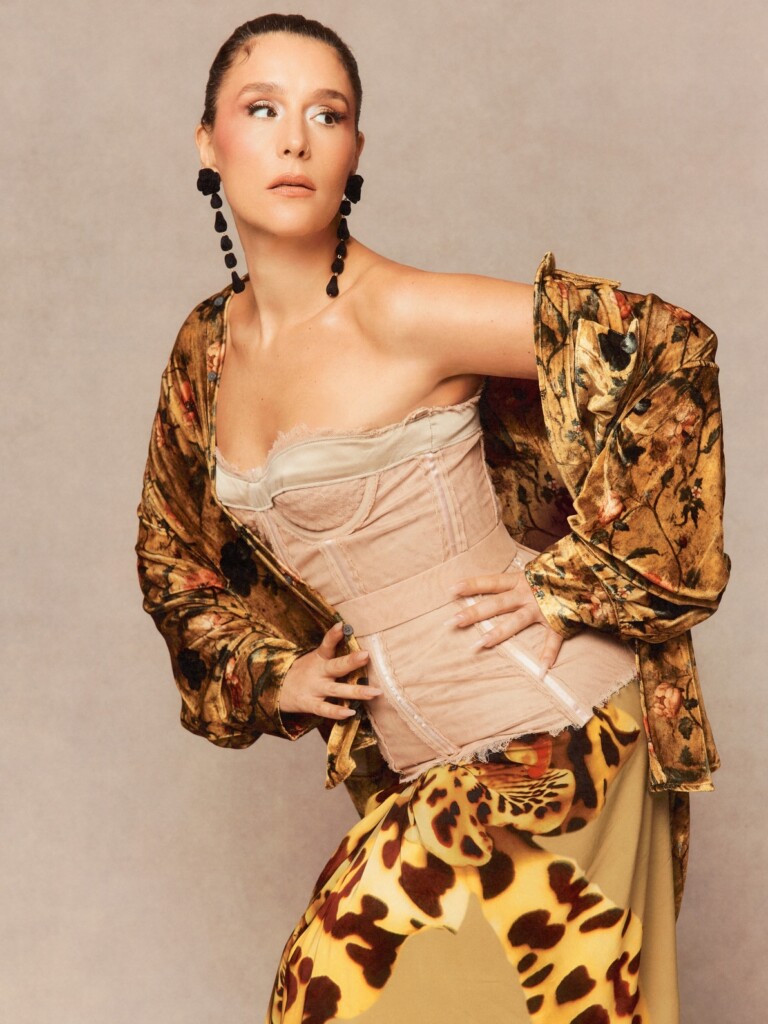 Fashion model posing in a gold floral robe over a beige corset with a leopard-print skirt, looking left.