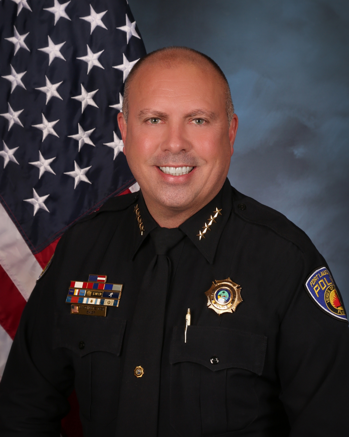 2nd Annual Pride Center Drag Brunch: At Seminole Hard Rock Hotel & Casino Hollywood | Hotspots Magazine Hotspots Magazine Male police officer in a dark uniform posing in front of the American flag, smiling confidently.