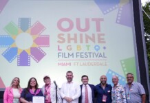 Group of eight people posing on a stage in front of a colorful Out Shine LGBTQ+ Film Festival banner reading Miami & Fort Lauderdale.