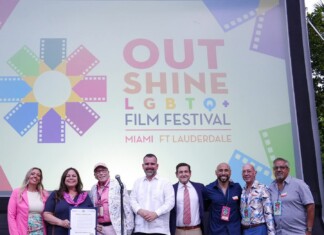 Group of eight people posing on a stage in front of a colorful Out Shine LGBTQ+ Film Festival banner reading Miami & Fort Lauderdale.