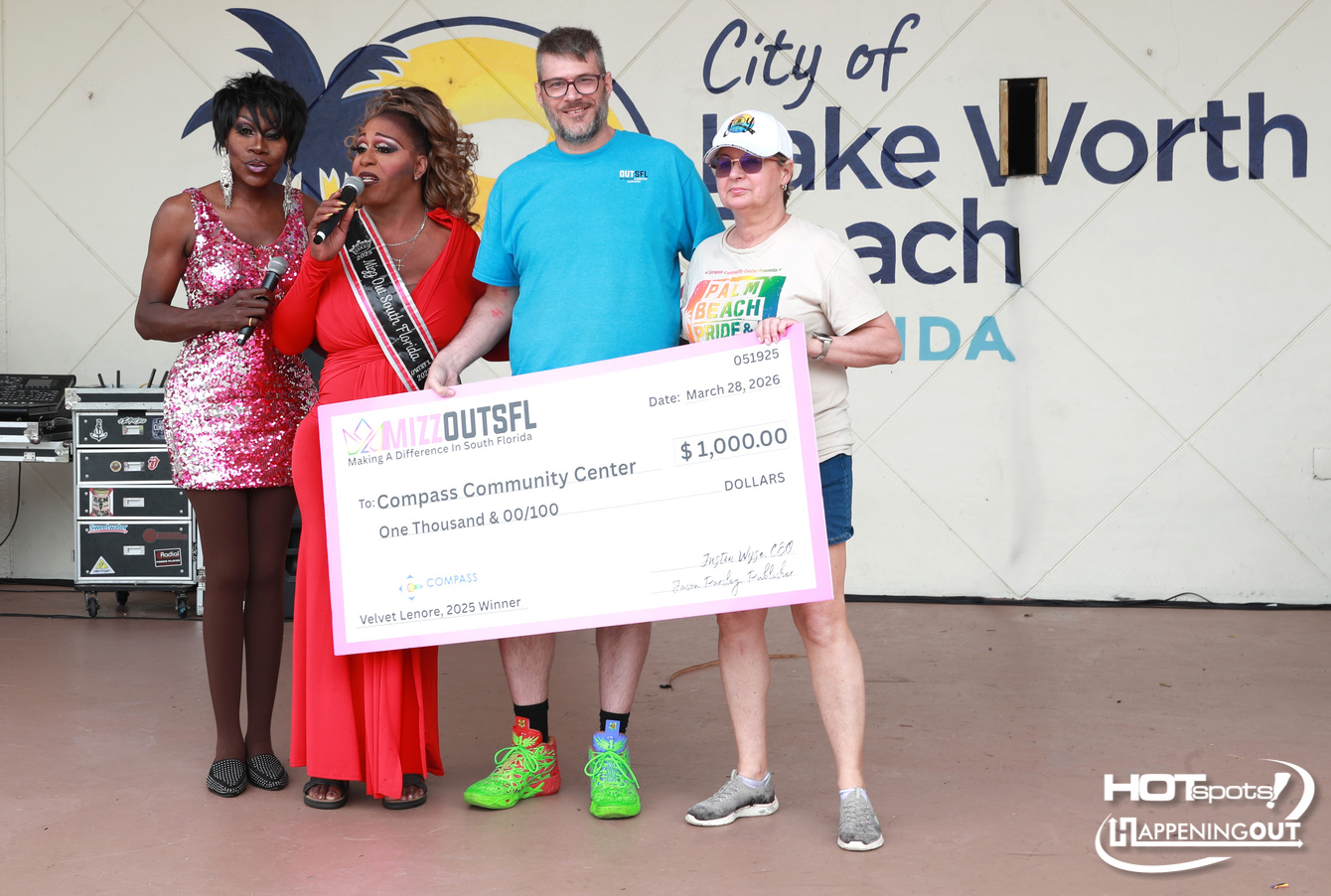 Group of four people posing on a stage with a large fake check for  alt=