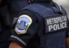 Metropolitan Police officer in navy uniform, back patch reads METROPOLITAN POLICE, close-up view.