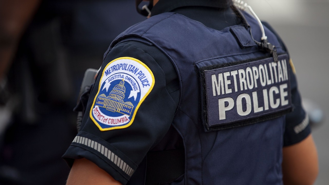 Metropolitan Police officer in navy uniform, back patch reads METROPOLITAN POLICE, close-up view.