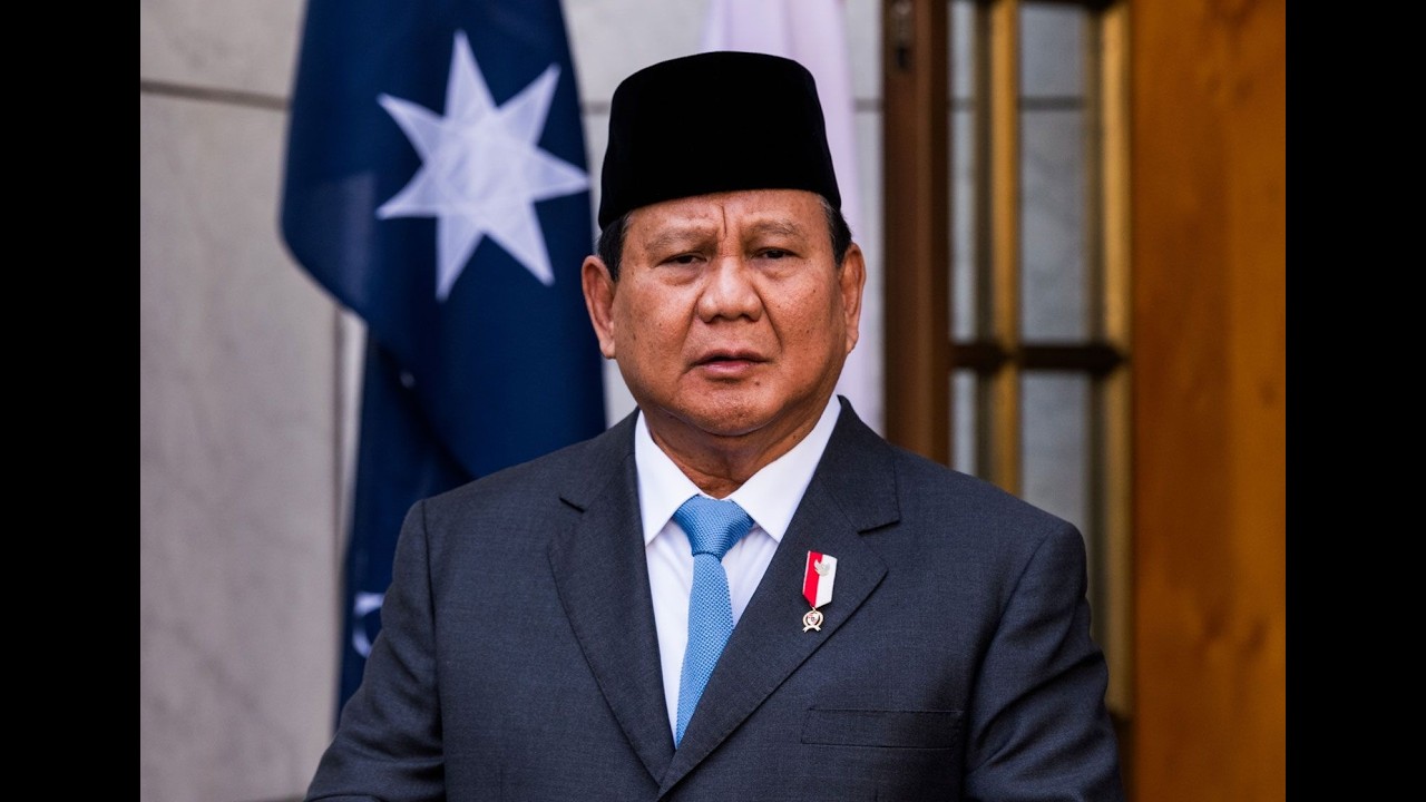 Homophobic Claims Against Presidential Aide Trigger Political Firestorm in Indonesia Formal portrait of a man in a dark suit and light blue tie, wearing a medal on his lapel, indoors with a flag in the background.