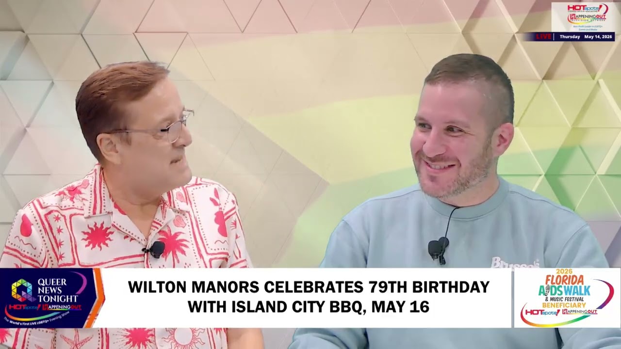 Wilton Manors Celebrates 79th Birthday With Island City BBQ, May 16 Two men sit side by side and smile during a TV talk show in a studio with a geometric pastel backdrop; a caption banner at the bottom mentions Wilton Manors' birthday event.