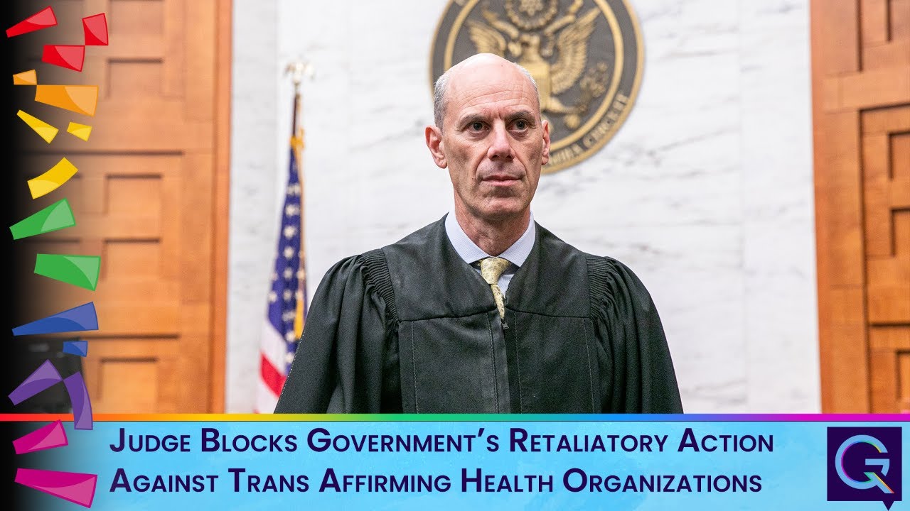Judge in robe stands in a courtroom; on-screen headline reads: 'Judge Blocks Government’s Retaliatory Action Against Trans Affirming Health Organizations'