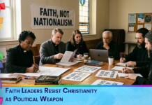 Group of faith leaders around a table, reviewing documents as a banner reading 'FAITH, NOT NATIONALISM' hangs in a room.