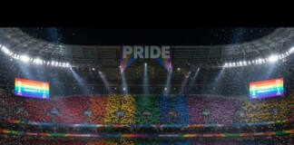 Fans in a stadium hold rainbow cards, creating a Pride banner across the stands beneath a large 'PRIDE' sign.