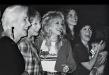 Five women posing and laughing together at a social event, enjoying the moment in a candid black-and-white photo.
