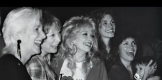 Five women posing and laughing together at a social event, enjoying the moment in a candid black-and-white photo.