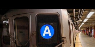 Subway train at a platform with a blue circular 'A' line symbol on the rear window.