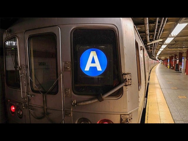 Subway train at a platform with a blue circular 'A' line symbol on the rear window.