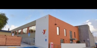Exterior of a YMCA building with orange and white walls, blue curb, and disabled parking spaces in the foreground.