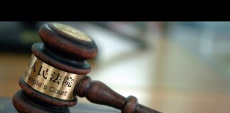 Wooden judge's gavel with a brass band reading 'People's Court' resting on a desk in a courtroom setting.