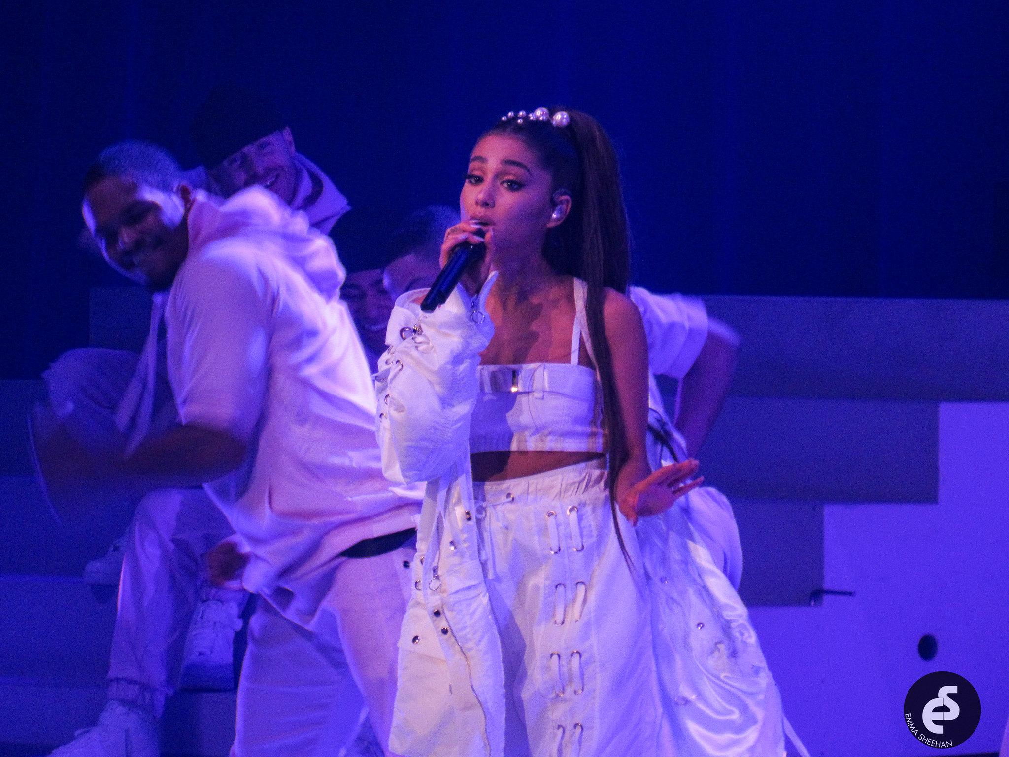 What’s Hot South Florida: June 19 – July 02 | Hotspots Magazine Hotspots Magazine Female singer in a white outfit singing into a microphone on a blue-lit stage, with backup dancers in white behind her.