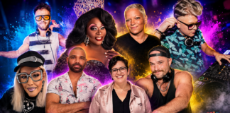 Eight club DJs and drag performers pose around a colorful stage with a mixer in the foreground.