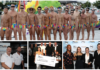 Group of men in rainbow-striped swimsuits posing shirtless on a dock with a boat and yellow-green balloons in the background