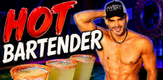 Muscular, shirtless bartender wearing a cap stands beside three salted margaritas on a neon-lit bar.