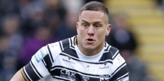 Male rugby player in a black-and-white striped jersey sprinting during a match.