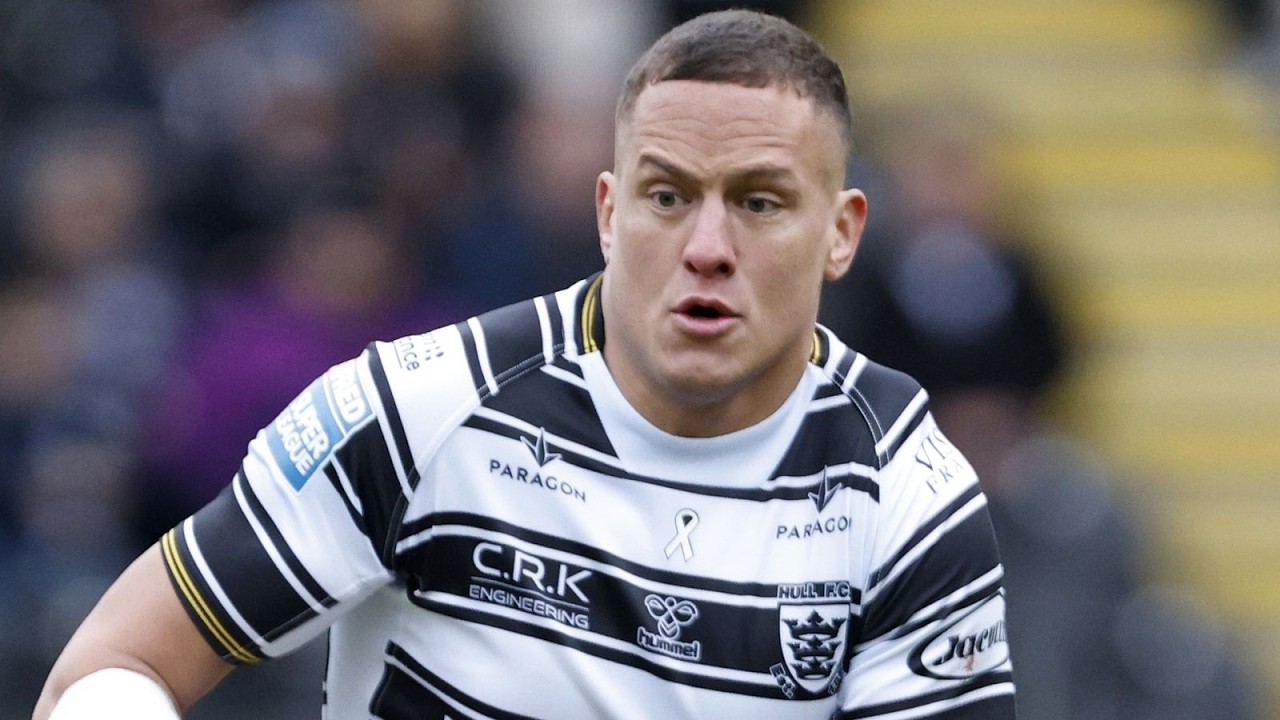 Male rugby player in a black-and-white striped jersey sprinting during a match.