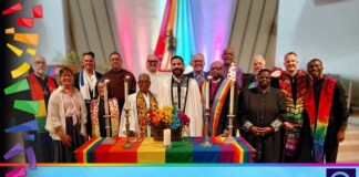 Group of diverse clergy around a rainbow altar at an interfaith Pride ceremony, banner below reads 'Bishop Robert Gives Reason for Interfaith Pride'.