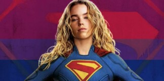 Woman in a blue Superman costume with red cape, hands on hips, against a rainbow-striped background.