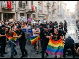Police form a barrier as LGBTQ2+ protesters march down a narrow street, holding rainbow flags and Turkish signs amid cheering crowds.