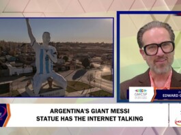 Split-screen news shot: left shows a giant statue of a soccer player in a blue-and-white jersey; right shows a male anchor with glasses.