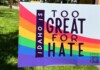 Rainbow Pride sign outdoors reading 'Too Great for Hate' with 'Idaho' vertical; Pride resources QR code in the lower corner.