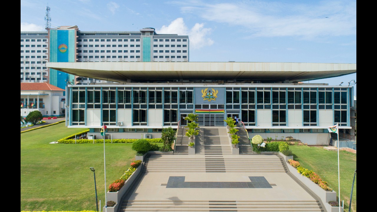 Ghana Parliament Approves Bill Criminalizing LGBTQ+ Identity Modern government building with a wide staircase, flanked by greenery, and a central emblem above the entrance.
