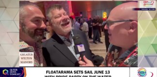 Three men at a media interview on a Pride event set, smiling while a reporter holds a mic in a crowded venue (Greater Wilton Manors Pride).