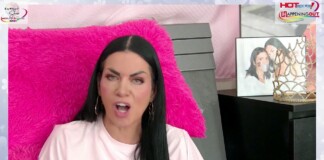 Woman with long black hair wearing a pink shirt, speaking from a pink fluffy chair with a crown decor and framed photo on a black dresser nearby.