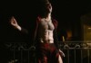Beartooth Singer Caleb Shomo Comes Out as Gay Following 14-Year Marriage Shirtless man shouting on a balcony at night, wearing red pants and an open red jacket.