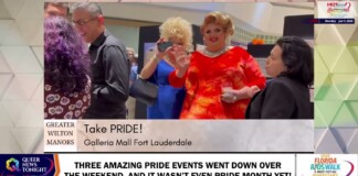 Group of people at a Pride event posing and waving, with a banner reading 'Take PRIDE! Galleria Mall Fort Lauderdale'