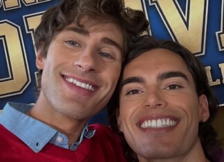 Popular Gay Sports Romance Waterboy Returns With Sequel Season on ReelShort Two men smiling for a selfie in front of a blue and gold banner at an event.