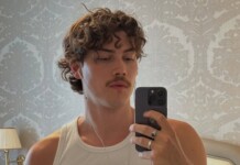 Jack Innanen Forced to Pass on Heated Rivalry Season 2 Role Due to Scheduling Conflicts Young man in a white tank top taking a mirror selfie with earphones in a wallpapered bedroom