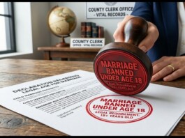 Close-up of a red stamp reading 'MARRIAGE BANNED UNDER AGE 18' pressed onto a legal form on a wooden table, with a hand nearby and office signage in the background (county clerk).