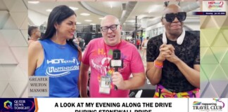 Three TV hosts in a studio during a Pride segment: center man with a microphone and media badge, flanked by a woman in blue and a man in sunglasses; on-screen headline references Stonewall Pride and a lower-third banner.