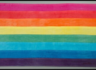 Rainbow horizontal flag with pink, red, orange, yellow, green, blue, and purple stripes laid flat, representing LGBTQ Pride.
